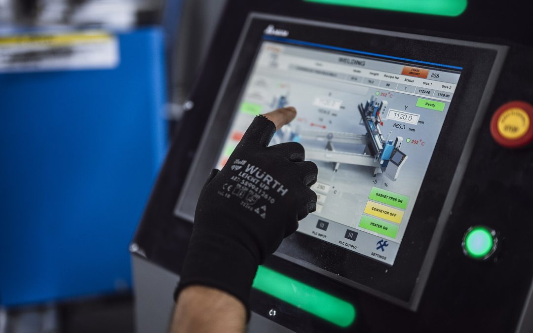 Factory operator using an industrial machine control panel, illustrating human oversight of automated control systems