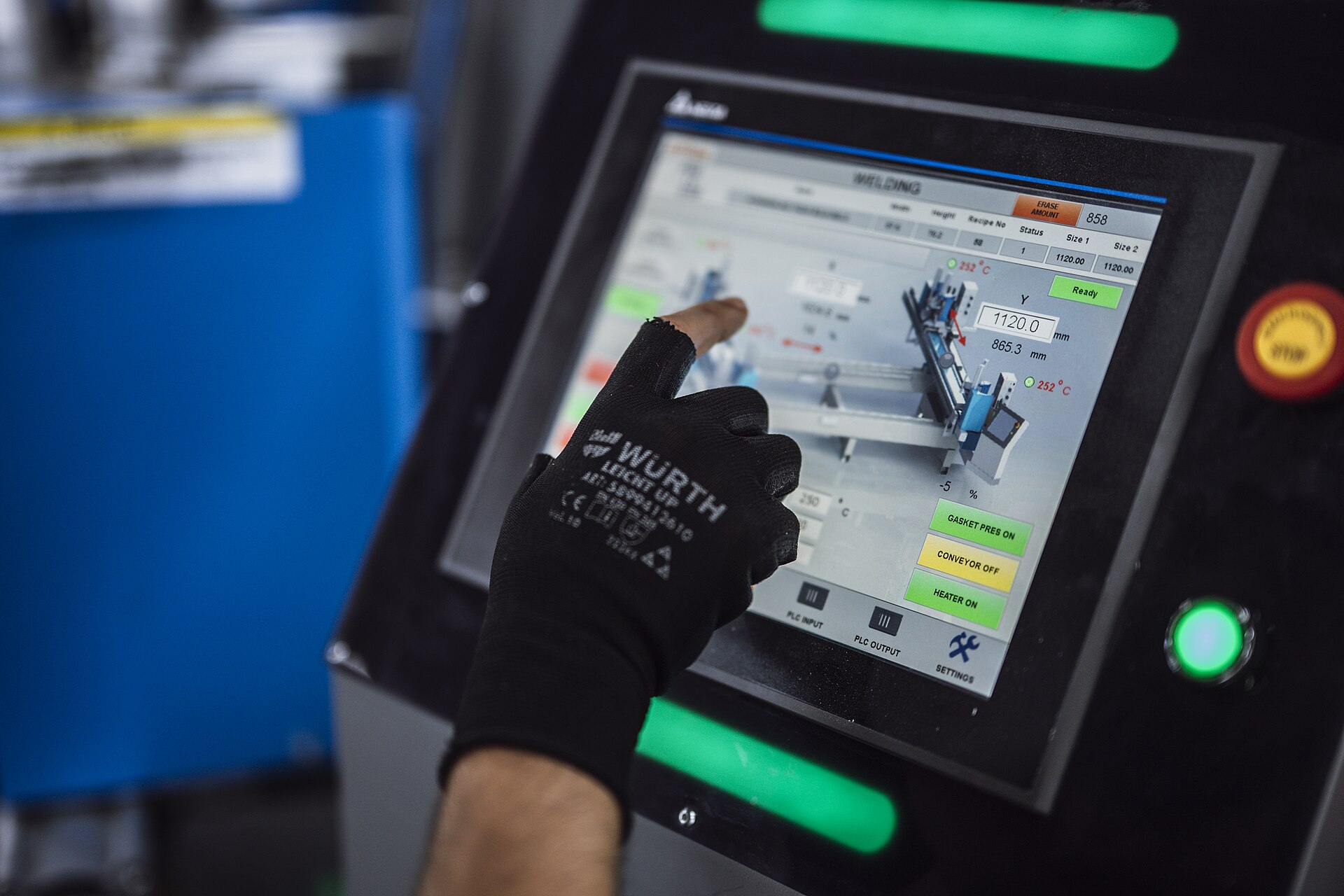Factory operator using a machine control panel, illustrating human oversight of AI-assisted industrial control